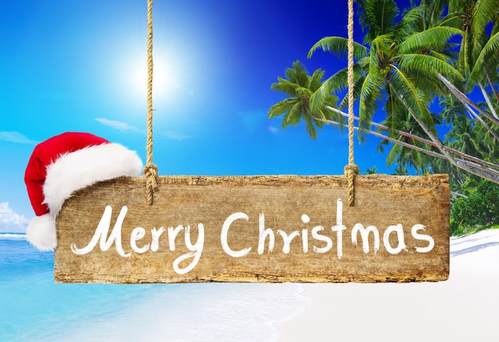 Merry Christmas sign with Santa hat on a tropical beach