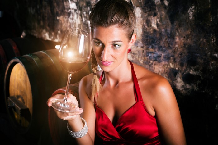 Woman in red dress holding wine glass in cellar