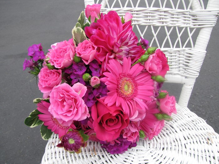 Pink and purple flower bouquet on a white wicker chair