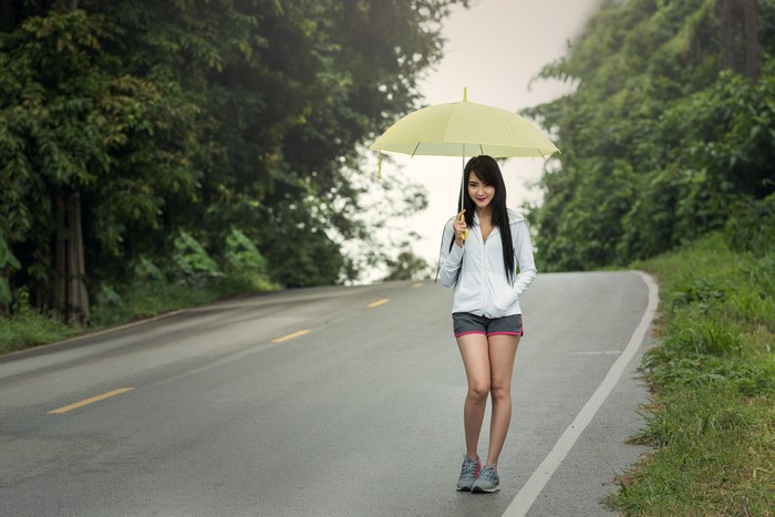 Brunette girl with umbrella on a wet road