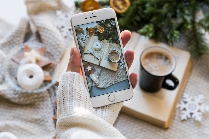 Smartphone showing winter scene with book and coffee