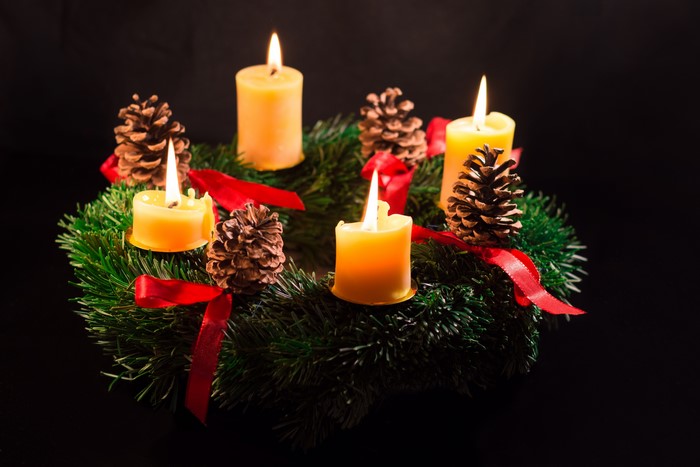 Advent wreath with four lit candles and pine cones