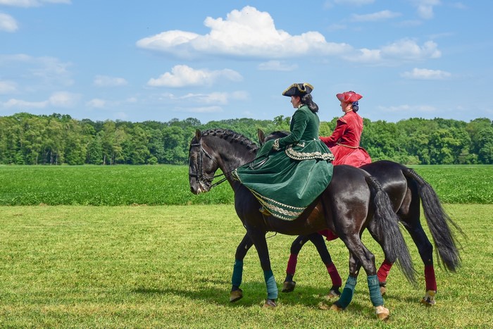 Two women in historical attire riding horses