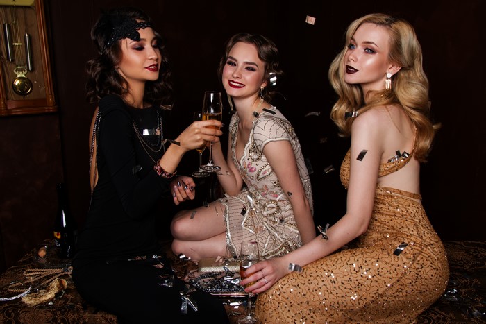 Three women in glamorous dresses with champagne