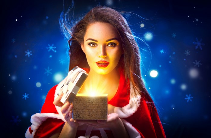 Woman in Santa costume opening a glowing gift box