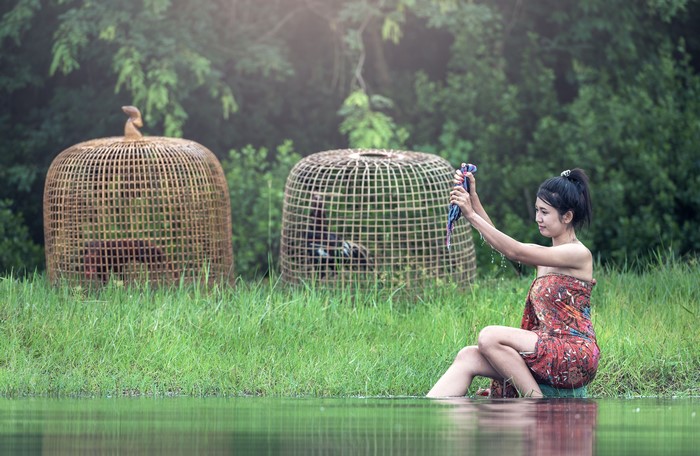 Brunette girl washing clothes by the water