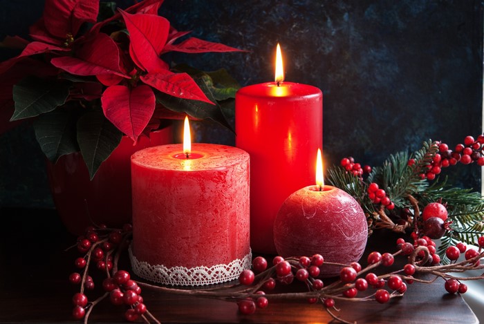 Christmas candles with poinsettia and berries