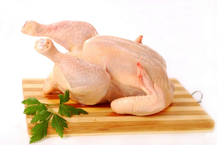 Raw chicken on a cutting board with parsley