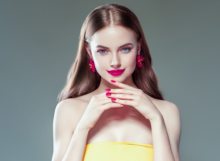 Woman with pink earrings and yellow top
