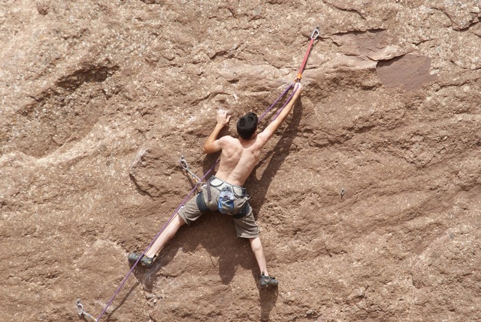 Man rock climbing on a brown crag