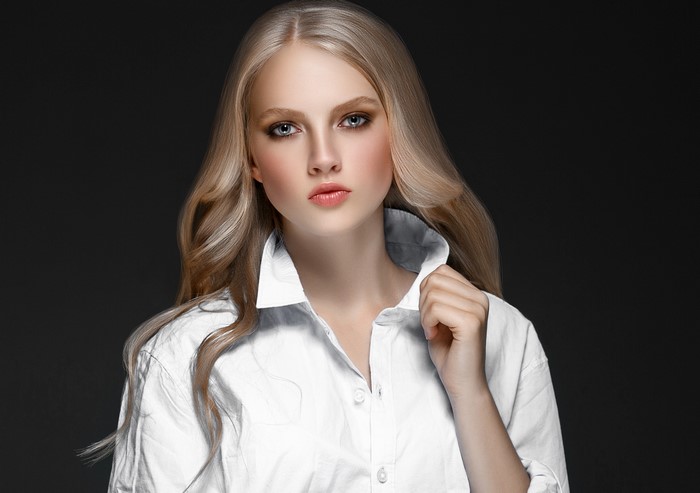 Blonde woman in white shirt on gray background