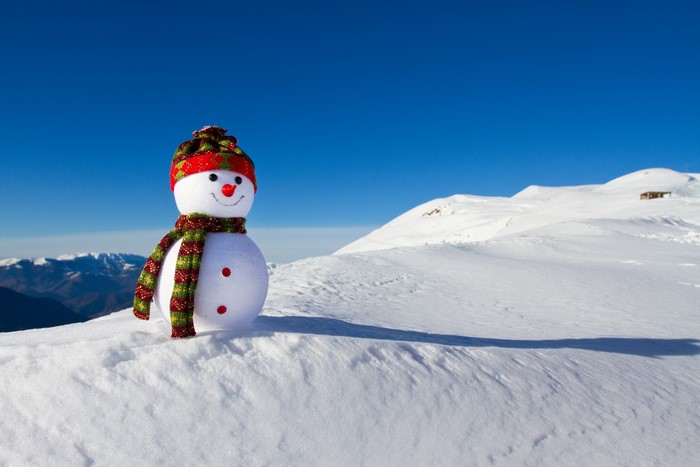 Snowman with hat and scarf in snowy mountains
