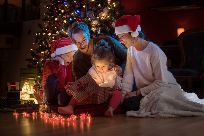 Family opening Christmas gifts by the tree