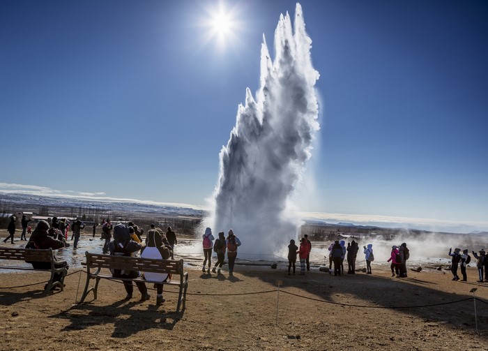 Geyser Strokkur erupting in Iceland with tourists