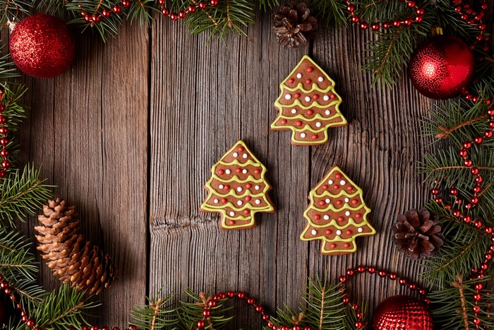 Christmas tree cookies on wooden planks with pine cones and ornaments