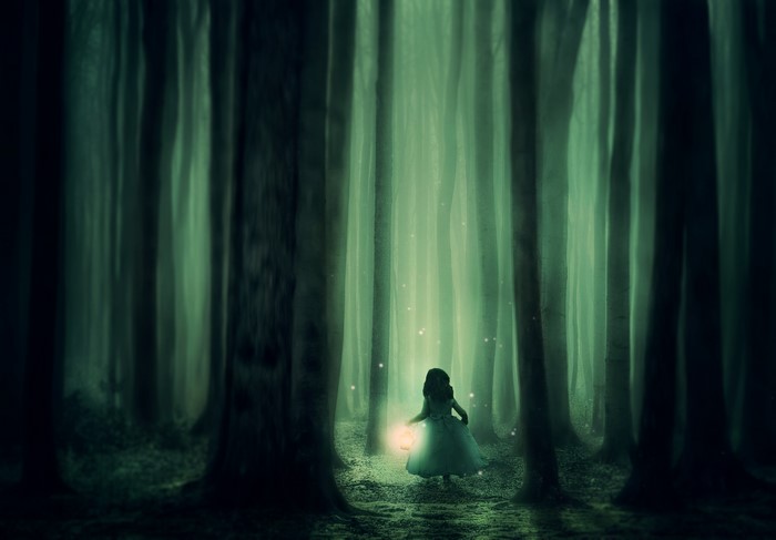 Girl with lantern in a foggy forest