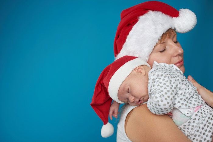 Mother holding sleeping baby in Santa hats