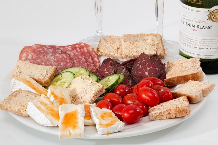 Cheese, Salami, Biltong, Bread, Tomatoes, Cucumbers on Plate with Wine