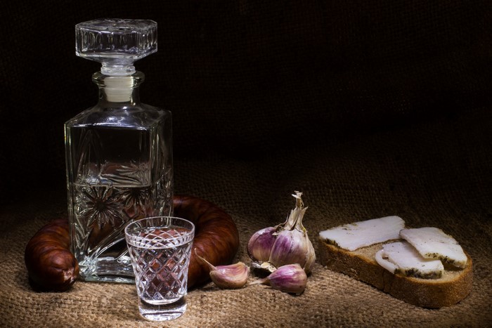 Vodka bottle, shot glass, sausage, garlic, and salo on bread