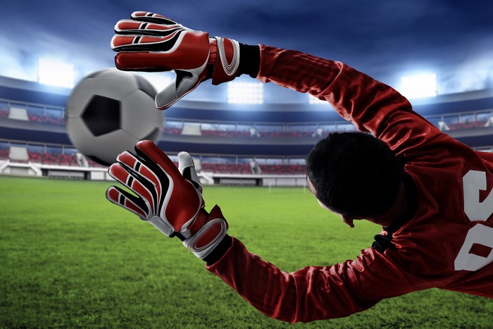 Goalkeeper jumping to catch a soccer ball in a stadium