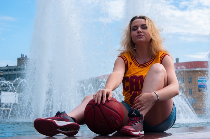 Blonde girl with basketball sitting by fountain