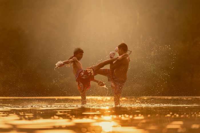 Two boys practicing Muay Thai in a river