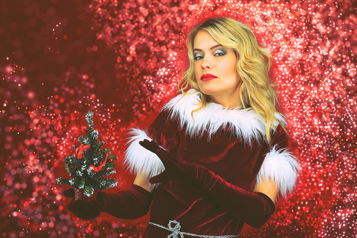 Woman in Santa costume holding a Christmas tree