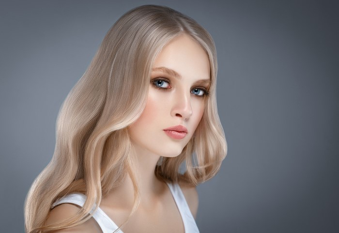 Blonde woman with wavy hair on gray background