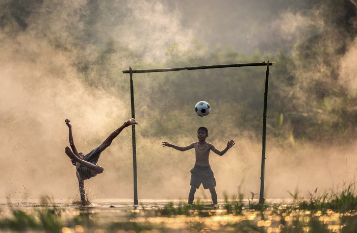 Boys playing football in foggy water