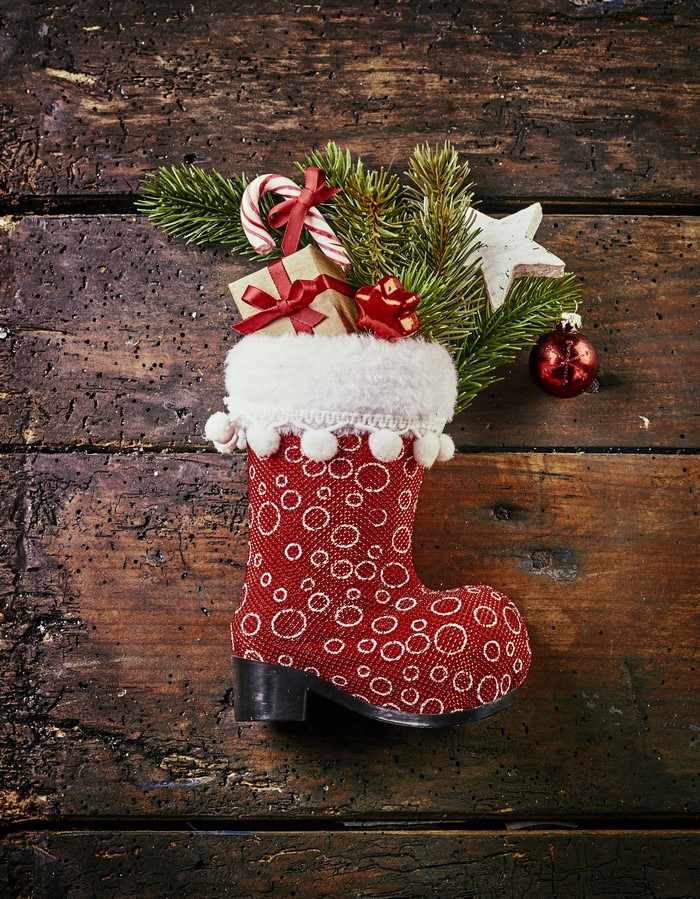 Christmas stocking with gifts and ornaments on wood
