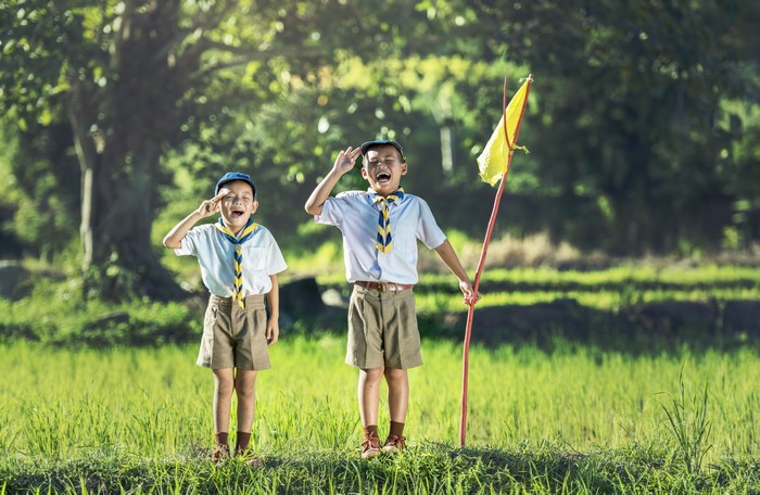Two Asian boys in scout uniforms with a flag