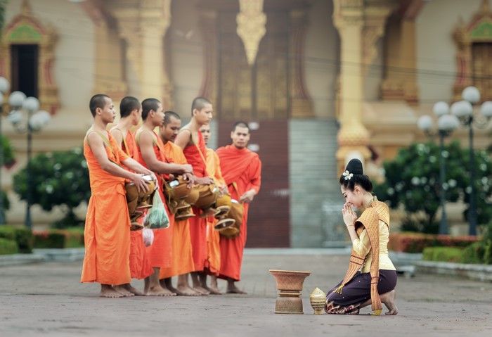 Monks receiving alms from a woman in traditional clothing