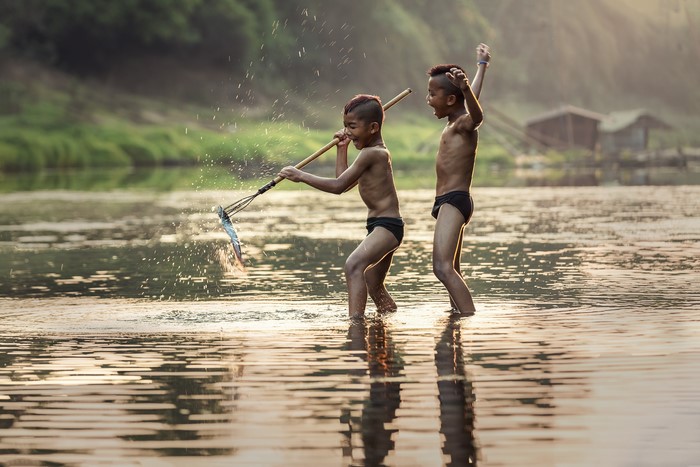 Two Asian boys fishing in a river