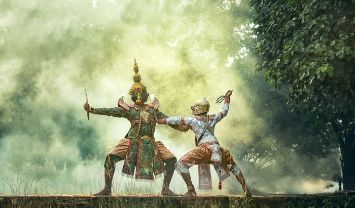 Two masked dancers in traditional Asian costumes fighting