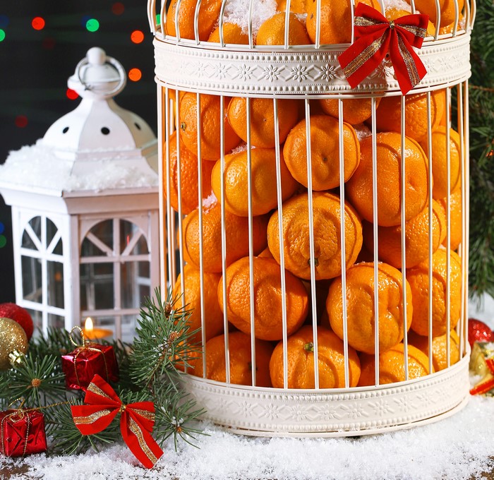 Christmas tangerines in a decorative cage with snow and gifts