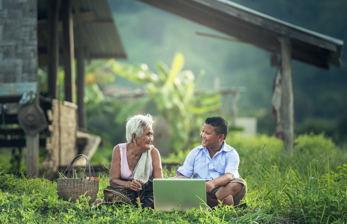 Old woman and boy with laptop in grass