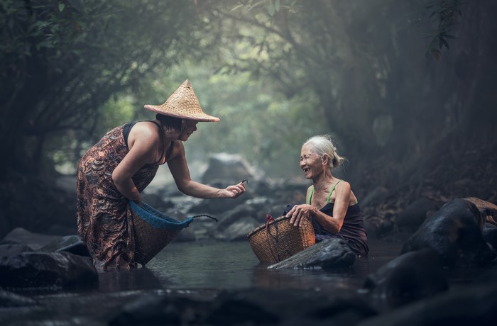 Two Asian women in a stream with baskets