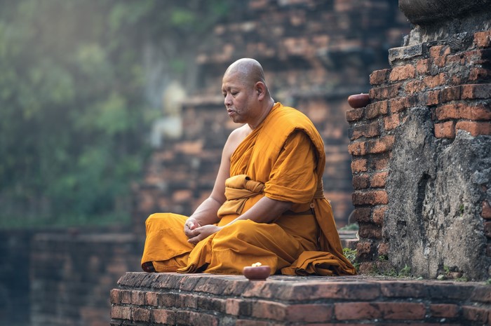 Buddhist monk meditating on ancient ruins