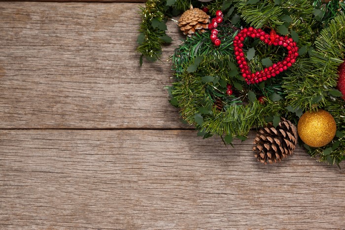 Christmas wreath with pine cones and ornaments on wood
