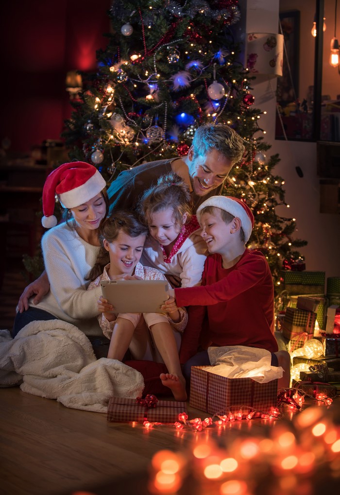 Family looking at a tablet by a Christmas tree