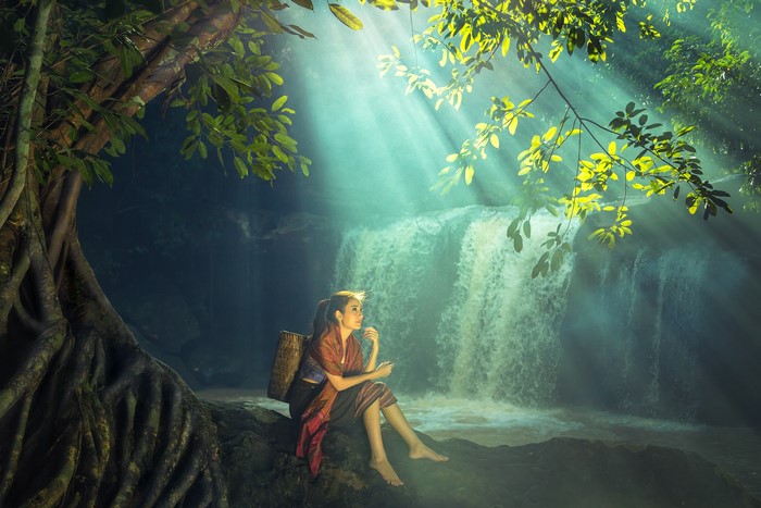 Asian woman sitting by a waterfall