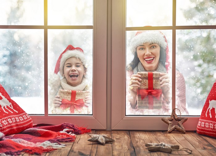 Mother and daughter with Christmas gifts at window