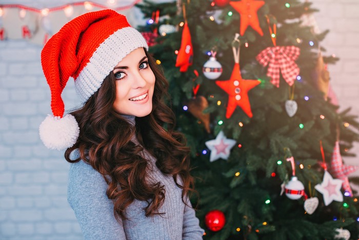 Woman in Santa hat by Christmas tree