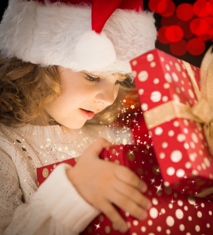 Girl in Santa hat opening a Christmas gift