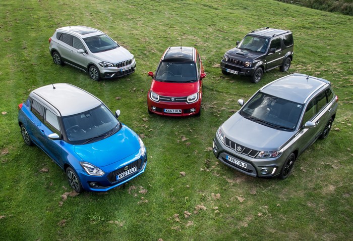 Five Suzuki cars parked on a grassy hill