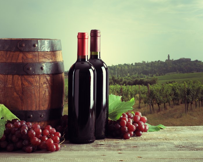 Wine bottles, grapes, and barrel in a vineyard