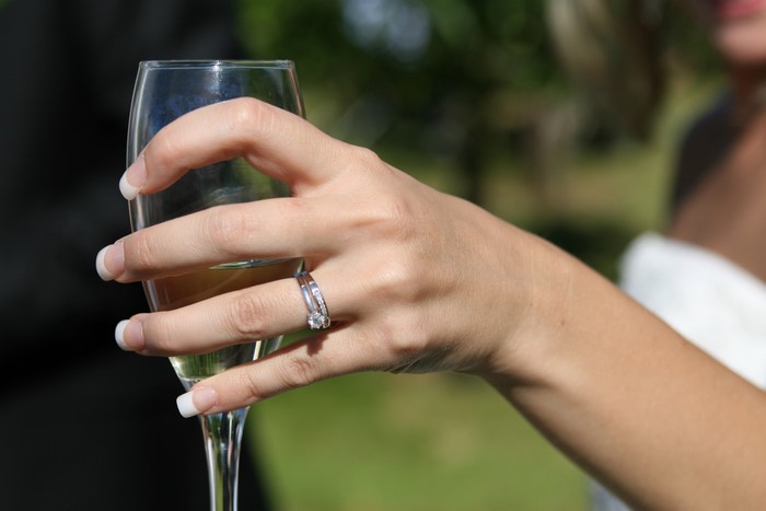 Woman's hand with rings holding a champagne glass