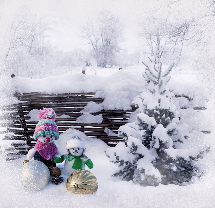Two snowmen with winter hats and scarves in the snow