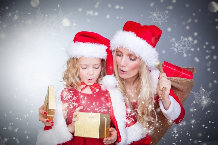 Mother and daughter in Santa costumes opening Christmas gifts