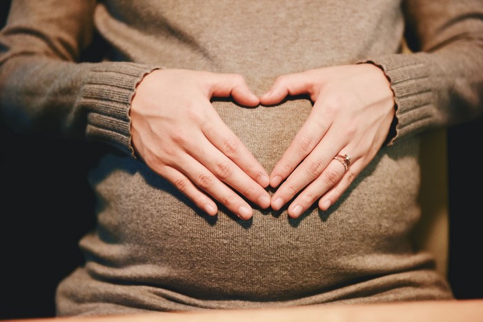 Pregnant belly with hands forming a heart